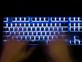 رجل يكتب على لوحة مفاتيح الكمبيوتر ذات الإضاءة الخلفية - المصدر: بلومبرغ