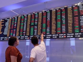 أحد الزائرين يشير إلى اللوحة الإلكترونية لحركة الأسهم في بورصة"بي 3"، ساو باولو، البرازيل - المصدر: بلومبرغ