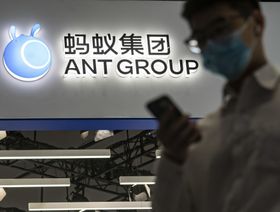 شخص يعبر من أمام لوحة مضاءة تحمل شعار شركة "آنت غروب" الصينية - المصدر: بلومبرغ