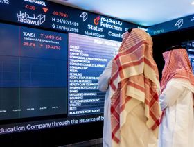 شخصان يطالعان بيانات أسعار الأسهم على لوحة معلومات إلكترونية في سوق الأسهم السعودية 'تداول'. صورة أرشيفية - المصدر: بلومبرغ
