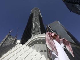 رجل يعبر من أمام برج في مركز الملك عبدالله المالي في العاصمة السعودية الرياض - المصدر: بلومبرغ
