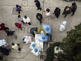 سكان يصطفون أمام مجموعة من الكوادر الصحية للخضوع إلى اختبار "كوفيد-19" في أحد أحياء مدينة شنغهاي الصينية في 26 مارس 2022 - المصدر: بلومبرغ
