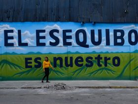 إمرأة تمر أمام لوحة جدارية كُتب عليها "إيسيكويبو لنا" في إشارة إلى المنطقة المتنازع عليها، وذلك يوم التصويت على الاستفتاء في العاصمة الفنزويلية كاراكاس، الأحد في 3 ديسمبر 2023 - المصدر: بلومبرغ