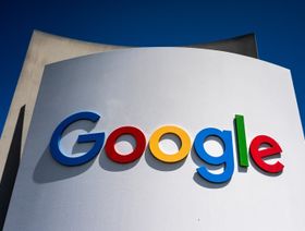 لافتة تحمل شعار شركة "جوجل" بألوانه المميزة مثبتة على مبنى أبيض تحت سماء زرقاء صافية - بلومبرغ