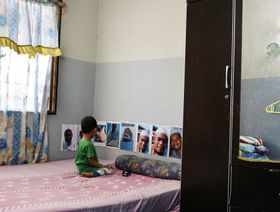 الابن الأصغر لهاني بن شاعري ينظر إلى صور والده في منزل العائلة في سانغاي رامباي، ماليزيا. - المصدر: بلومبرغ