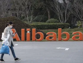 فتاة تمر أمام شعار مجموعة "علي بابا" عند مقرها في مدينة هانغتشو، الصين - المصدر: بلومبرغ
