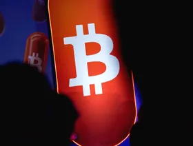 شعار عملة بتكوين. العملة المشفرة هبطت دون 100 ألف دولار، مع اجتياح موجة عزوف عن المخاطرة الأسواق ودفعها المستثمرين إلى سحب ما يقرب من 900 مليون دولار من الصناديق. - بلومبرغ