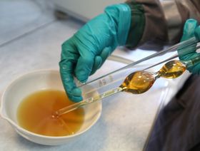 موظف يختبر جودة عينة من الزيت بعد استخلاصه جراء عملية تكرير النفط - المصدر: بلومبرغ