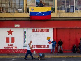 مشاة بالقرب من لوحة جدارية كتب عليها "إيسيكويبو  هي فنزويلا" في كاراكاس، فنزويلا   - المصدر: بلومبرغ