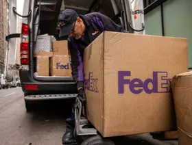 عامل يقوم بنقل الطرود من شاحنة فيديكس في نيويورك - بلومبرغ