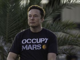 إيلون ماسك مرتدياً قميصاً كُتب عليه "احتلوا المريخ" (Occupy Mars) - المصدر: بلومبرغ
