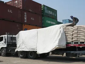 عامل يفرش غطاءً على شاحنة محملة بالأسمنت في ميناء سوندا كلابا في جاكرتا، إندونيسيا - بلومبرغ