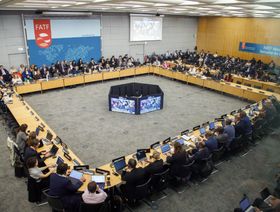 اجتماع لمجموعة العمل المالي بمشاركة ممثلين من مختلف الدول، حيث يجلس المشاركون حول طاولة مستديرة وأمامهم حواسيب وشاشات كبيرة - بلومبرغ