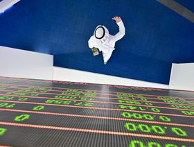 متداول يمشي أسفل لوحة عرض الأسهم في بورصة دبي في الإمارات العربية المتحدة - المصدر: أ.ف.ب