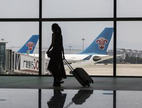 انعكاس ظل امرأة تحمل أمتعة أثناء سيرها أمام طائرة تشغلها " تشاينا ساوثرن ايرلاينز"  في المبنى رقم 2 بمطار قوانغتشو باييون الدولي، الصين - المصدر: بلومبرغ