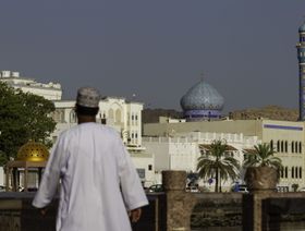 مواطن عُماني يسير على طول الواجهة البحرية لكورنيش مطرح الذي  تصطف على جانبيه منازل التجار التي تعود للقرن التاسع عشر في مدينة مسقط القديمة، عمان. - المصدر: بلومبرغ