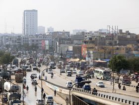 حركة المرور على طول الطريق السريع ويظهر مبنى سكني شاهق مشيد حديثاً في الخلفية في كراتشي في باكستان - المصدر: بلومبرغ