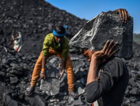عمال يحملون قطعاً من الفحم في ساحة بالقرب من منجم للفحم في سونبادرا بولاية أوتار براديش، الهند  