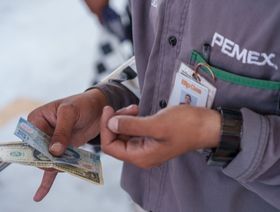 عامل يمسك بإكراميات تلقاها بالدولار الأميركي والبيسو المكسيكي في محطة وقود شركة "بتروليوس ميكسيكيانوس"أو "بيميكس" في سيوداد خواريز بولاية تشيهواهوا في المكسيك - المصدر: بلومبرغ