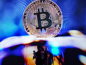 شعار عملة بتكوين المشفرة على مسكوكة معدنية - بلومبرغ