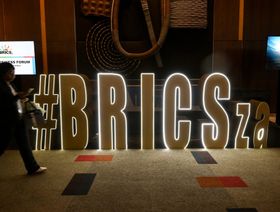 زائرة تعبر من أمام شعار مجموعة "بريكس" في مركز ساندتون للمؤتمرات حيث تعقد أعمال القمة 15 للمجموعة في منطقة ساندتون بجوهانسبرغ، جنوب أفريقيا، يوم الثلاثاء، 22 أغسطس 2023. - المصدر: بلومبرغ