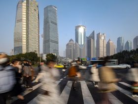 عدد من المارة يعبرون الطريق في منطقة لوجياتسوى المالية بحي بودونغ في شنغهاي - المصدر: بلومبرغ