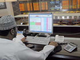 مستثمر يتابع أسعار الأسهم على جهاز كمبيوتر خاص أمام شرفة مطلة على قاعة التداول في سوق مسقط للأوراق المالية في مسقط، سلطنة عمان (صورة أرشيفية) - المصدر: رويترز