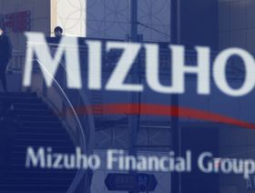انعكاس  صور المشاة في لافتات خاصة بـ "ميزوهو فاينانشال غروب"خارج فرع مصرف " ميزوهو بنك" في طوكيو ، اليابان - المصدر: بلومبرغ