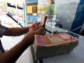 شخص يعد أوراقاً نقدية فئة 25 ألف دينار عراقي داخل أحد محلات الصرافة في بغداد، العراق (أرشيفية) - رويترز 