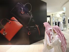 متسوقان بالزي الوطني السعودي يمران أمام إعلان للحقائب الفاخرة في أحد المراكز التجارية في الرياض - بلومبرغ