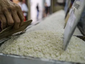 شخص يعدّل كومة من الأرز في أحد المتاجر - بلومبرغ