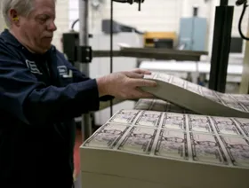 عامل يجهز أوراق نقد أميركية لتدخل مرحلة الترقيم في طابعة داخل مكتب طباعة العملة بالعاصمة واشنطن، الولايات المتحدة - المصدر: بلومبرغ