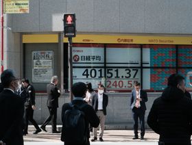 مشاة أمام لوحة أسهم إلكترونية تظهر مؤشر نيكاي 225 للأسهم خارج شركة للأوراق المالية في طوكيو، اليابان - المصدر: بلومبرغ