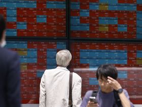 أحد المشاة ينظر إلى لوحة أسهم إلكترونية خارج شركة للأوراق المالية في طوكيو، اليابان - المصدر: بلومبرغ
