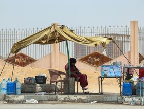 بائعة تجلس محتمية من حرارة الشمس في أحد ضواحي القاهرة - المصدر: بلومبرغ