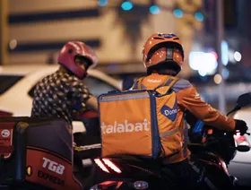 سائق تابع لشركة طلبات يتحدث مع سائق يعمل لدى "تي جي بي إكسبريس" في طريقهما لتوصيل طلبيات في الدوحة، دولة قطر - Getty Images