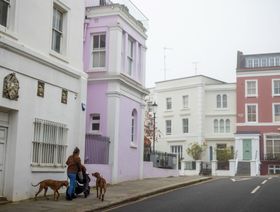 أحد المشاة ينزه كلاباً ومن وراءه عقارات سكنية ذات ألوان زاهية في منطقة كنسينغتون وتشيلسي، لندن، المملكة المتحدة - المصدر: بلومبرغ