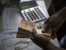 شخص  يعد  الأوراق النقدية من فئة 500 كوانزا في مكتب صرافة في لواندا ، أنغولا ، يوم الجمعة 8 نوفمبر 2013. - المصدر: بلومبرغ