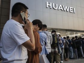 متسوقون أمام أحد متاجر "هواوي" في بكين - بلومبرغ