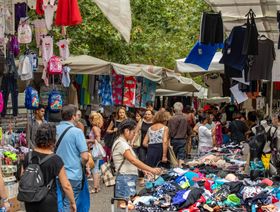 متسوقون يشترون الملابس في سوق بمدينة ميلانو، إيطاليا - المصدر: بلومبرغ