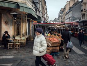 مشاة يمرون أمام عربة لبيع للفواكه والخضروات في سوق بوفو في باريس، فرنسا. 