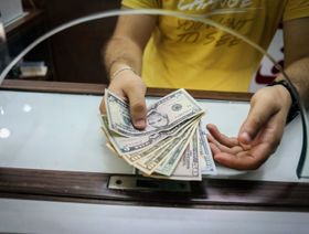 شخص يمسك أوراقاً نقدية من الدولار الأميركي - المصدر: بلومبرغ