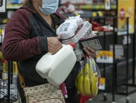 سيدة تحمل مواد بقالة أثناء انتظارها للدفع داخل متجر - المصدر: بلومبرغ