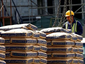 عامل يرتدي معدات السلامة، يشرف على تحميل أكياس أسمنت من صناعة شركة "أسمنت الرياض" بواسطة رافعة في موقع إنشاءات، الرياض، السعودية - رويترز