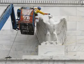 عامل ينظف تمثال النسر على مبنى مجلس الاحتياطي الفيدرالي في واشنطن - بلومبرغ