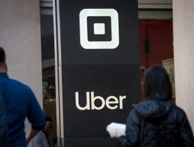 يمر المشاة أمام اللافتات المعروضة خارج المقر الرئيسي لشركة "أوبر" في سان فرانسيسكو، كاليفورنيا، أميركا، يوم الثلاثاء 6 أغسطس 2019. - المصدر: بلومبرغ