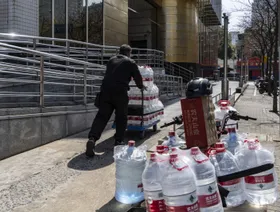 عامل توصيل يدفع عربة مملوءة بزجاجات مياه شركة "نونغفو سبرينغ" في شنغهاي. - بلومبرغ