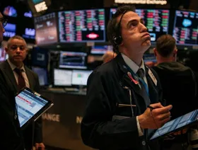 موظف في شركة تجارة أسهم في قاعة التداول ببورصة نيويورك للأوراق المالية - المصدر: بلومبرغ