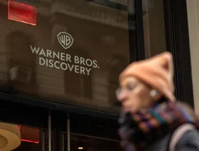 امرأة تمر أمام مقر "وارنر برذرز ديسكفري" في نيويورك، الولايات المتحدة الأميركية. - بلومبرغ