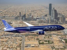طائرة تحمل شعار "طيران الرياض" تحلق بسماء العاصمة السعودية، ويبدو بالأفق مركز الملك عبدالله المالي - المصدر: بلومبرغ